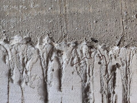 Unfinished lightweight concrete block wall texture with gray cement mortar joints and messy patches.