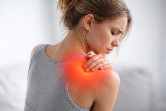 Woman feeling shoulder pain, experiencing back discomfort and ache