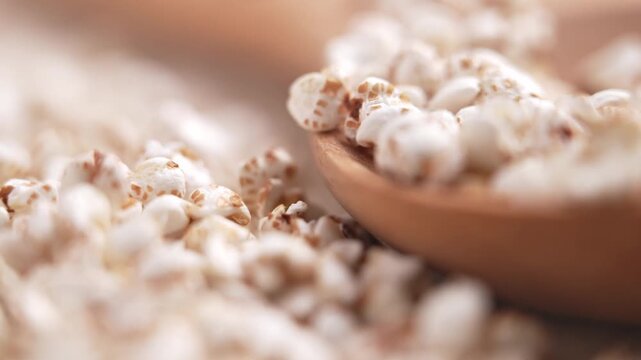 Crispy puffed buckwheat pouring on table with rustic timber spoon. Gluten-free grains