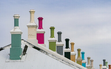 Naklejka premium Colourful and characterful chimneys sit on top of a line of semi-detached houses in District Six in Cape Town.