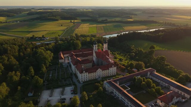 Drone landscape of Roggenburg in Bavaria featuring the baroque monastery complex, farmland, rural settlement and evening light, capturing the cultural heritage of the Schwaben region in late spring