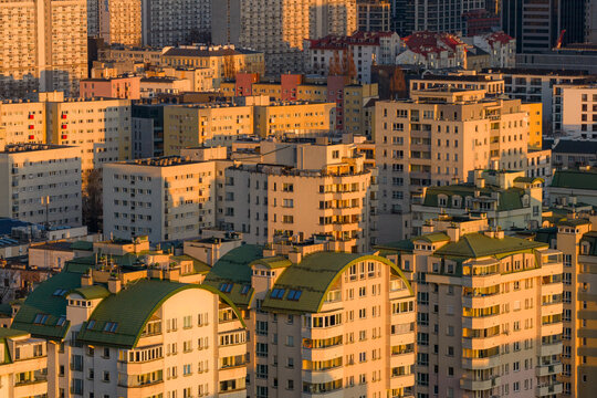 Aerial view of dense residential apartment blocks with green curved roofs during golden hour light in Warsaw, Masovian Voivodeship, Poland.