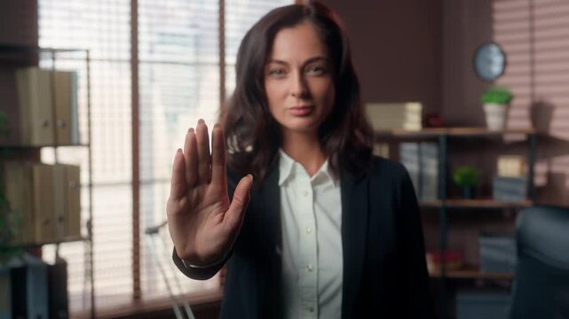 Serious Caucasian business woman showing stop gesture with open palm in office businesswoman looking at camera female manager warning refusal no sign professional employee indoors workplace conflict