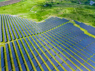 Hillside solar installations integrate seamlessly with lush fields. Aerial view showcasing renewable energy infrastructure harmoniously embedded in pastoral terrain © DSMT