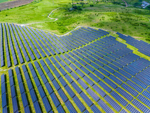 Hillside solar installations integrate seamlessly with lush fields. Aerial view showcasing renewable energy infrastructure harmoniously embedded in pastoral terrain