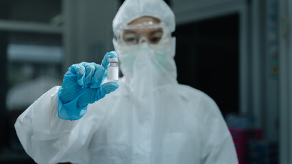 PPE Healthcare Worker Holds Hantavirus Vaccine Vial in Dark Clinic Setting © อภิสิทธิ์ ปักเหนือ