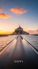 Obraz premium Historic Island Abbey Rising Above Tidal Causeway at Colorful Sunset