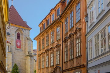 Obraz premium Beautiful historic street view in Prague featuring elegant Baroque building facades and the Church of Our Lady beneath the Chain.