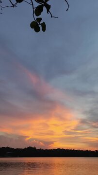 Video footage of a lake view on a warm afternoon with a reddish twilight sky showing the sunset in portrait format 