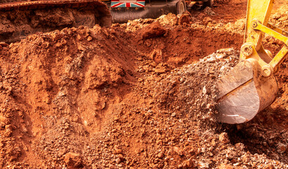 Backhoe digging soil at construction site. Bucket of backhoe digging soil. Crawler excavator digging on dirt. Excavating machine. Earth moving machine. Excavation vehicle. Backhoe working on suny day. © Fahroni