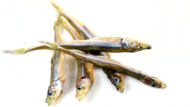 Smelt fish dried salted snack isolated on white background close up, Small fish heap of European smelt, Candlefish. Osmeridae, Osmerus eperlanus, Osmerus mordax close-up, top view, rotating