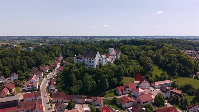 Aerial drone view of Voehlinschloss in Illertissen, Bavaria, Germany, showing the hilltop castle, town center and red roofs across the Schwaben region in the Neu Ulm district