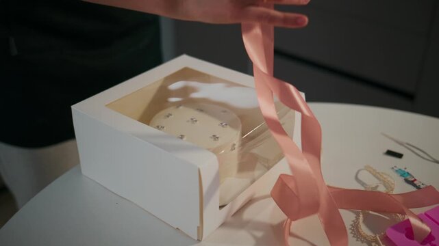 Woman tying a ribbon on a cake box in a confectionery shop