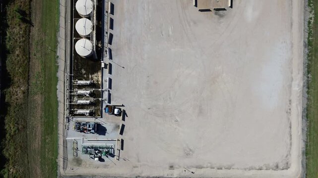Linear tank alignment at South Arlington operations yard beside grassy buffers, residential zones. Tank surfaces, piping shadows, gravel textures clean industrial pattern, municipal utility, TX