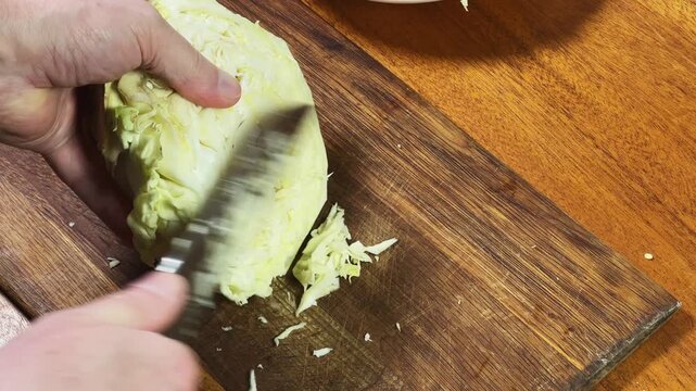 Shredding of white cabbage on cutting board for borscht cooking