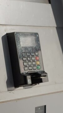 Vertical Screen: A POS terminal is mounted on a wall outside. It is exposed to the elements as it handles payment transactions. The device connects wirelessly for use.