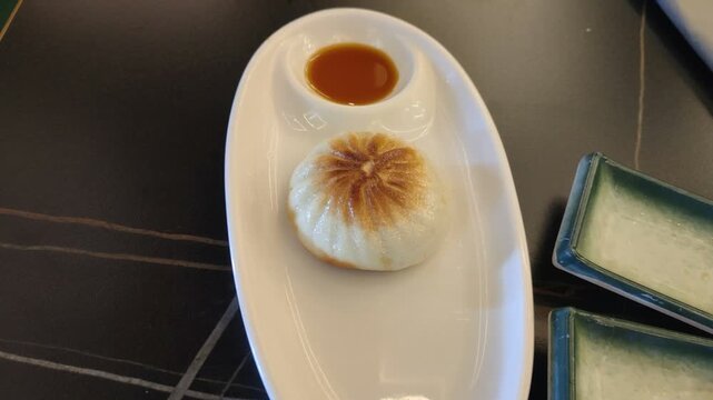 Pan-fried sheng jian bao dumpling served with soy sauce