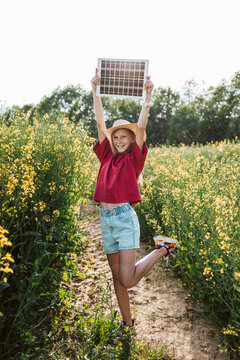 Girl holding solar panel in blooming field with sustainability concept.