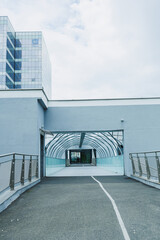 Fototapeta premium Walkway leads to a modern building with glass roof in an urban area during a cloudy day