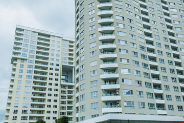 Naklejka premium Large modern apartment buildings in an urban area under a cloudy sky with multiple balconies visible on each floor