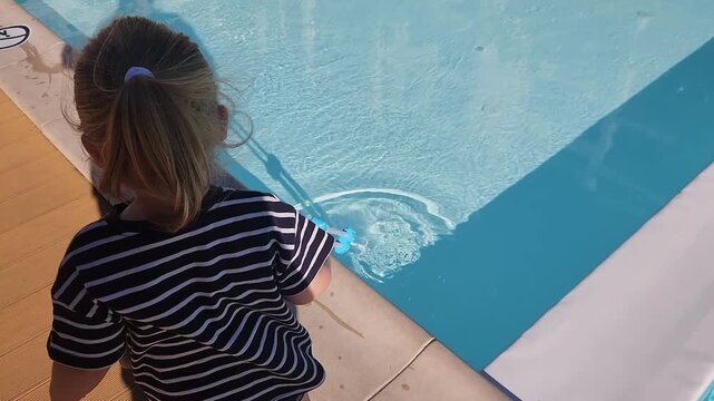 Toddler girl Sofia making ripples in a pool with a toy net