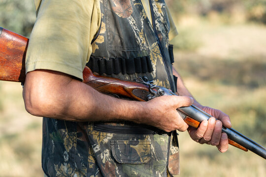 A hunter with a gun in camouflage clothing. A senior man with a gun, medium shot, searching for game.