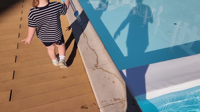 Shadow play and toddler legs on a sunny poolside deck