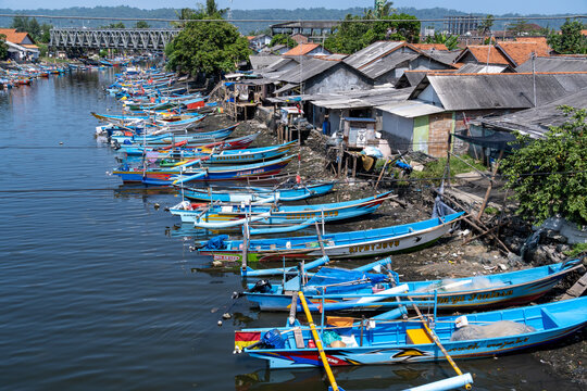 Cilacap, Indonesia - May 13, 2026: Traditional wooden fishing boats parked along a river canal in a coastal fishing village near Pelabuhan Perikanan Samudera Cilacap under a clear sky.