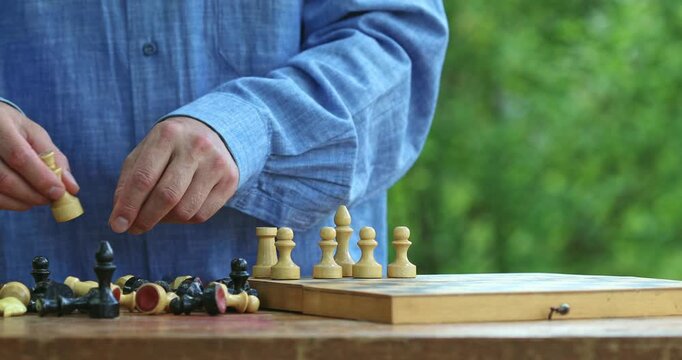 Man arrange chess pieces on wooden chessboard, ready for match, strategy and intellectual leisure game as hobby outdoor.
