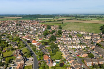Aerial view of modern housing development in Selby North Yorkshire bordered by farmland and countryside showing suburban growth and rural landscapes from above in the summer time © Duncan