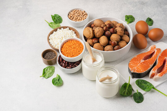 High protein food set with fresh salmon, eggs, cottage cheese, yogurt, lentils, chickpeas, beans and nuts arranged on white background with copy space