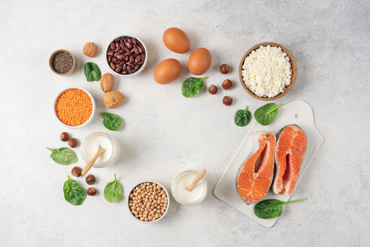High protein food set with fresh salmon, eggs, cottage cheese, yogurt, lentils, chickpeas, beans and nuts arranged on white background with copy space