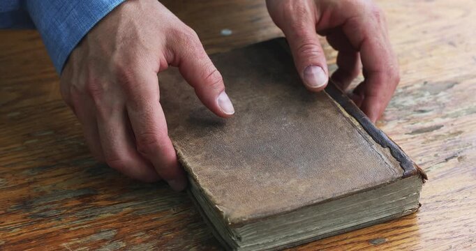 Aged vintage book in male hands. Pastor or priest with antique bible, historical literature or ancient wisdom and memory reading concept.