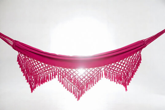 A vibrant pink macrame hammock or decorative textile is suspended against a bright white background.