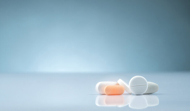 Pharmacy drugstore product. Pile of orange and white tablets pill on gradient background. Different size and shape tablets pills. Pharmaceutical industry. Medicine in hospital. Retail drug market.