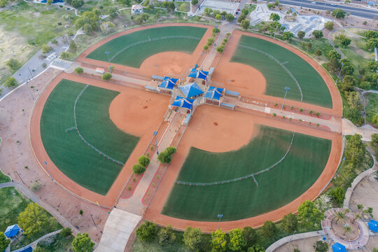 Aerial view of a baseball complex with four fields arranged in a circular pattern with red dirt and blue canopies in Summerlin South, Nevada, United States.