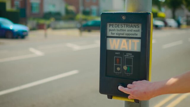 Pedestrian pressing crossing button at urban traffic light near busy road intersection. Street safety concept with wait signal appearing on pedestrian crossing control box. City transportation