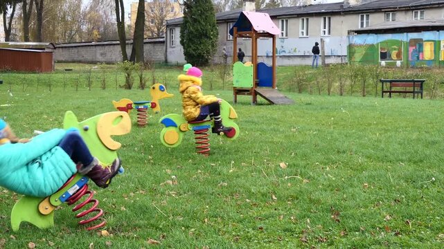 Two beautiful little girls on swing in autumn park