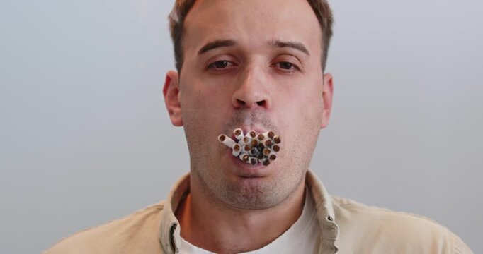 Man smoking cigarettes, smoke shows health harm. Many cigarettes burn, emitting toxic fumes that signal addiction, nicotine dependence, habit, danger, and lung damage. Quit now to save health.