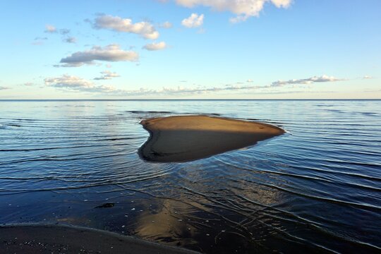 heart shaped sandbar in the calm lake under blue sky