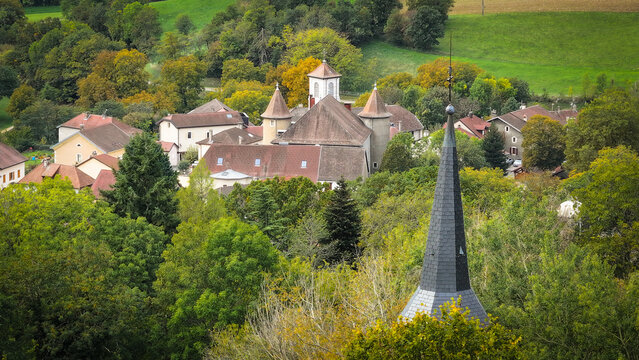 Aerial view of Chapelle Notre-Dame de Riantmont and the historic stone buildings surrounded by autumn foliage and rolling hills Vesancy, Auvergne-Rhone-Alpes, France.