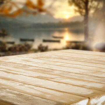 Empty wooden table with copy space for product placement, set against blurred summer landscape featuring a lake, blue sky,  warm sunshine and peaceful natural scenery.