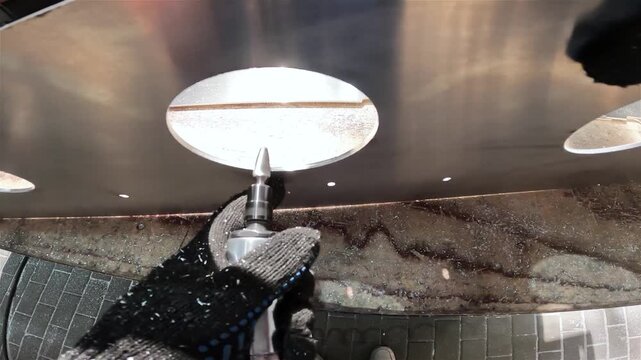 Grinding of an aluminum part.  worker processes an aluminum plate with a pneumatic grinder. Remove Sharp Edges and Burrs from Metal Parts. Carbide bur provides increased metal removal rates