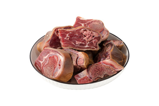 Raw cured ham hocks chopped into pieces in a white ceramic bowl isolated on white background