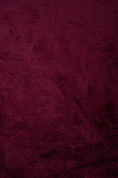 Dark red crushed velvet texture background, luxury burgundy velour fabric with soft shiny pattern.