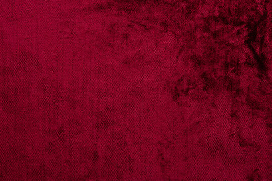Dark red crushed velvet texture background, luxury burgundy velour fabric with soft shiny pattern.
