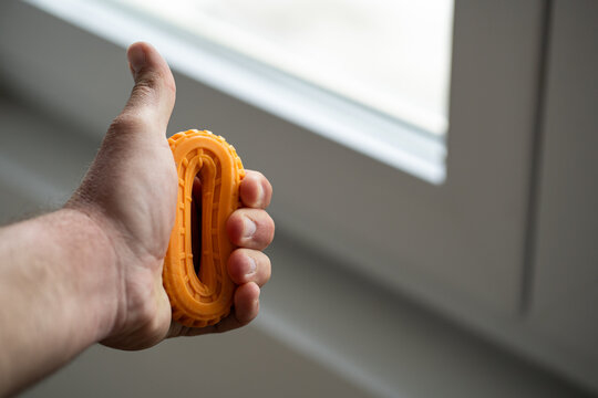 Close-up of a hand holding an orange grip strengthener ring
