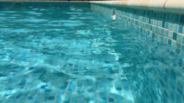 Pool water ripples casting abstract light patterns on wall