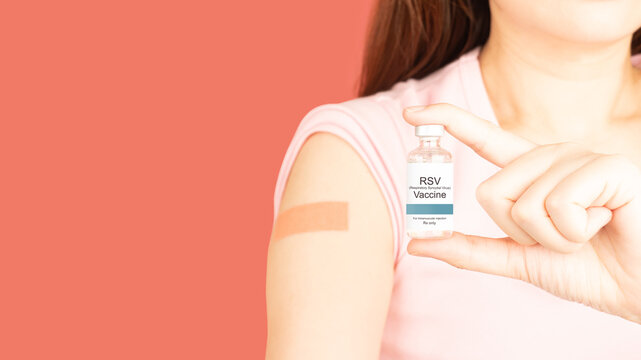 Woman showing vaccinated arm with medical adhesive bandage strip after RSV vaccine injection over pink background that protect pregnancy woman and infants from respiratory tract diseases.