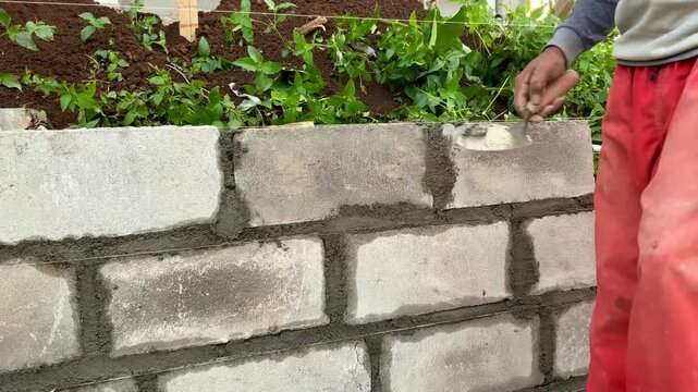 Construction worker laying concrete blocks to build a wall outdoors